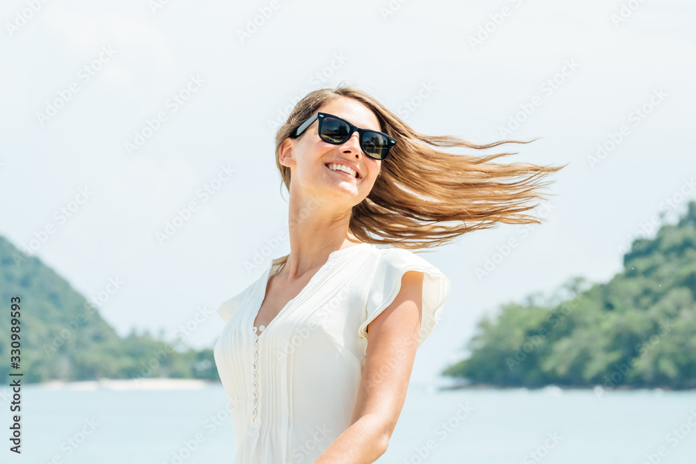 Smiling woman in white dress standing on beach. Sunny summer day Smiling woman in white dress standing on beach. Sunny summer day