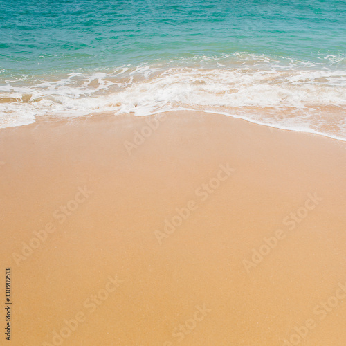 Soft blue ocean wave on sandy beach.