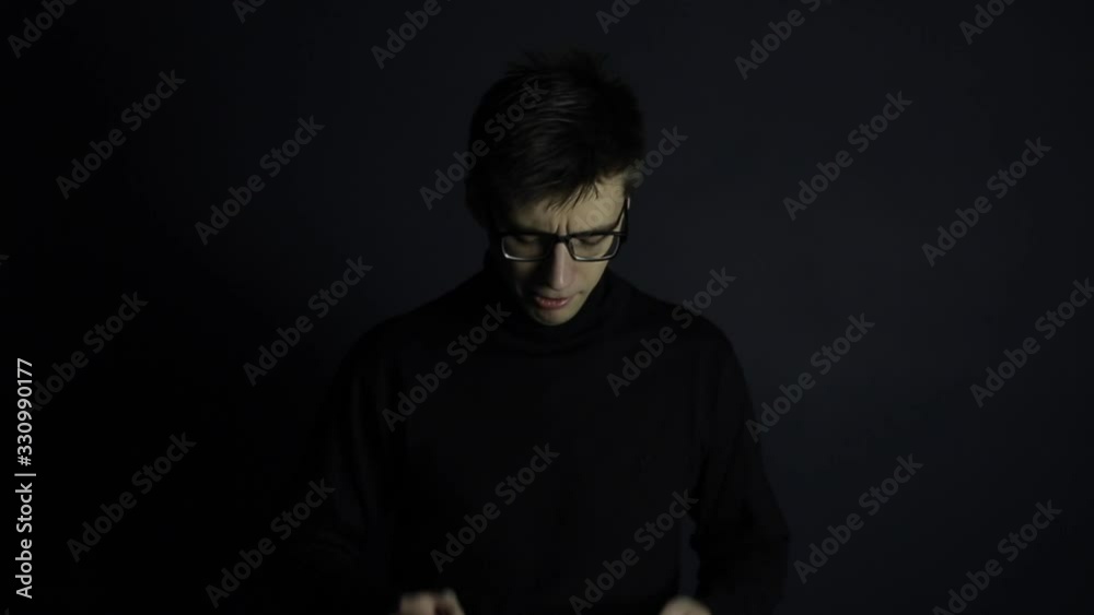 A young caucasian man coughing and putting on a medical mask. Isolated black background. Coronavirus COVID19 A young caucasian man coughing and putting on a medical mask. Isolated black background. Coronavirus COVID19