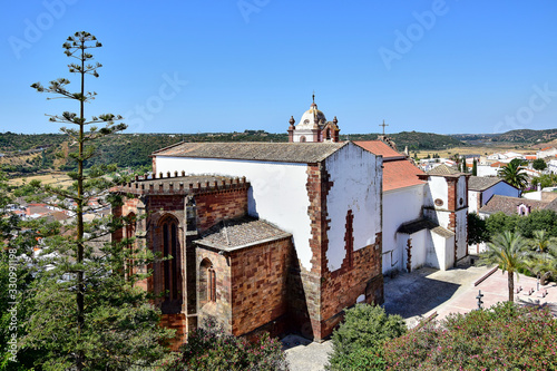 Silves / Algarve Portugal, Capela de Sao Francisco, a white and brown-faced building near the Silves fortress, trees and blue sky, in the summer during the daytime, view from the wall of the fortress