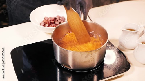 Closeup of chopped carrots in a large pan with chopped onions.