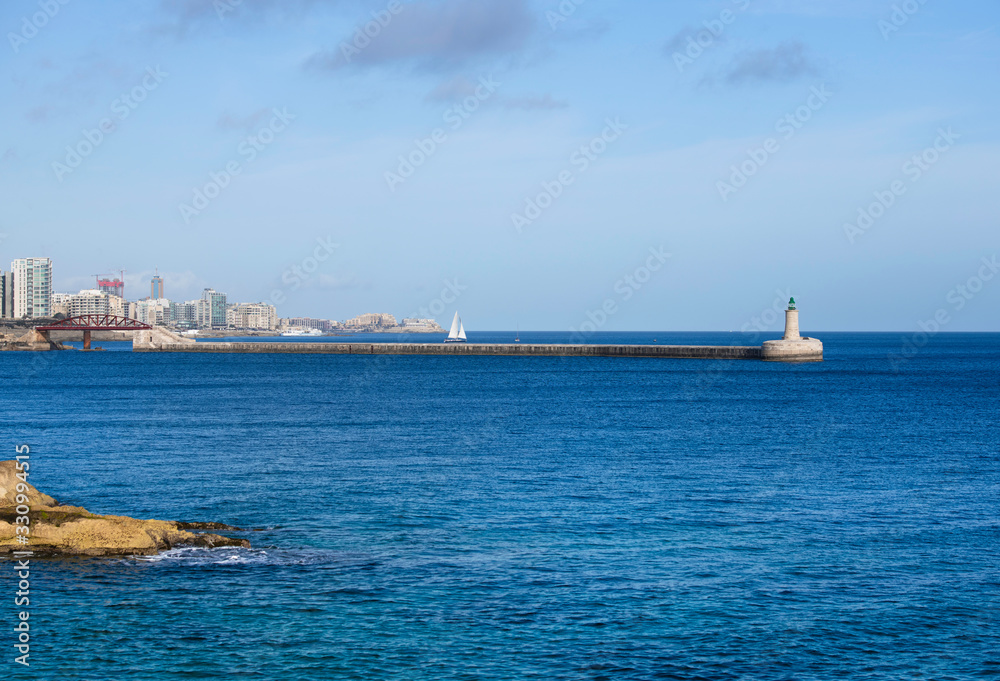 View of the old Saint Elmo Lighthouse, Valletta,Malta,Mediterranean Sea,Light tower.St Elmo Bridge or Breakwater Bridge,single-span arched truss steel sea footbridge in Valletta, Malta.Valletta bridge