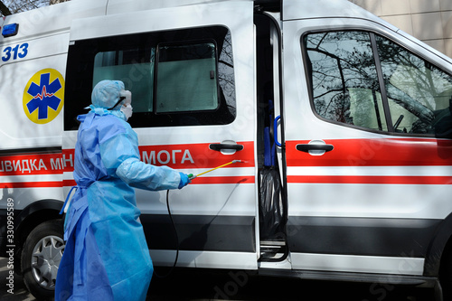 Fototapeta Naklejka Na Ścianę i Meble -  Paramedics disinfecting the ambulance car with the motorized backpack sprayer