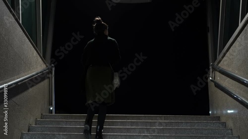 Woman walking the subway staircase alone at night. Horror, kidnap concept