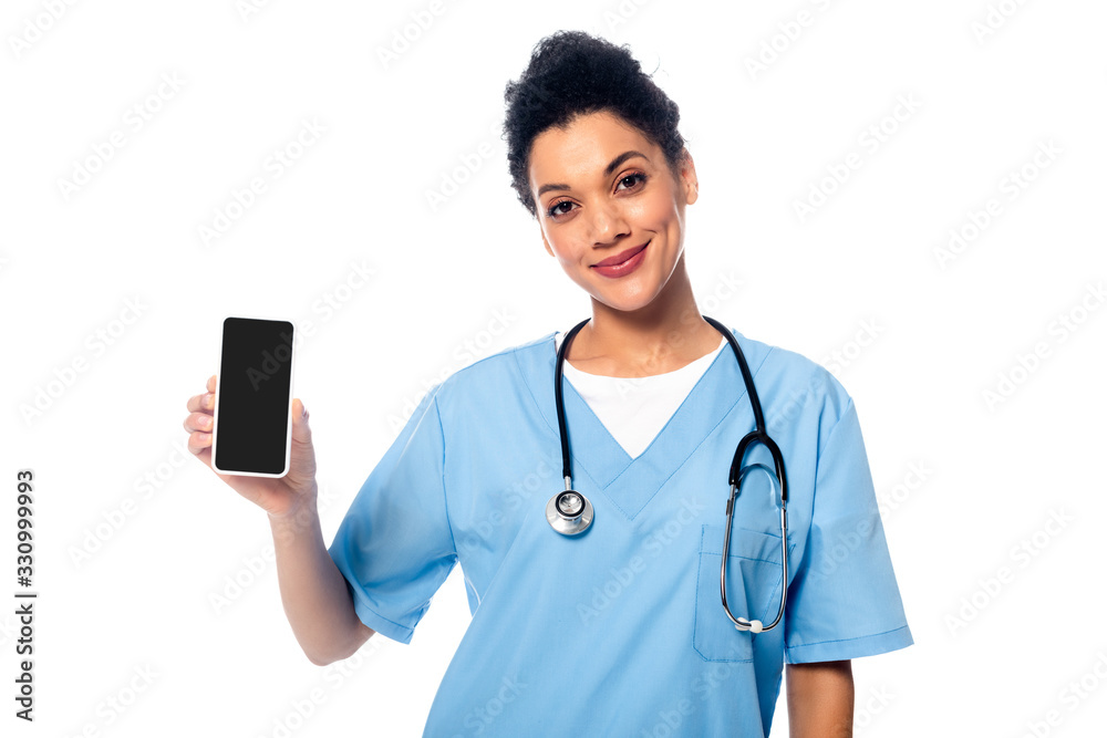 Front view of african american nurse with stethoscope smiling and showing smartphone isolated on white Front view of african american nurse with stethoscope smiling and showing smartphone isolated on white