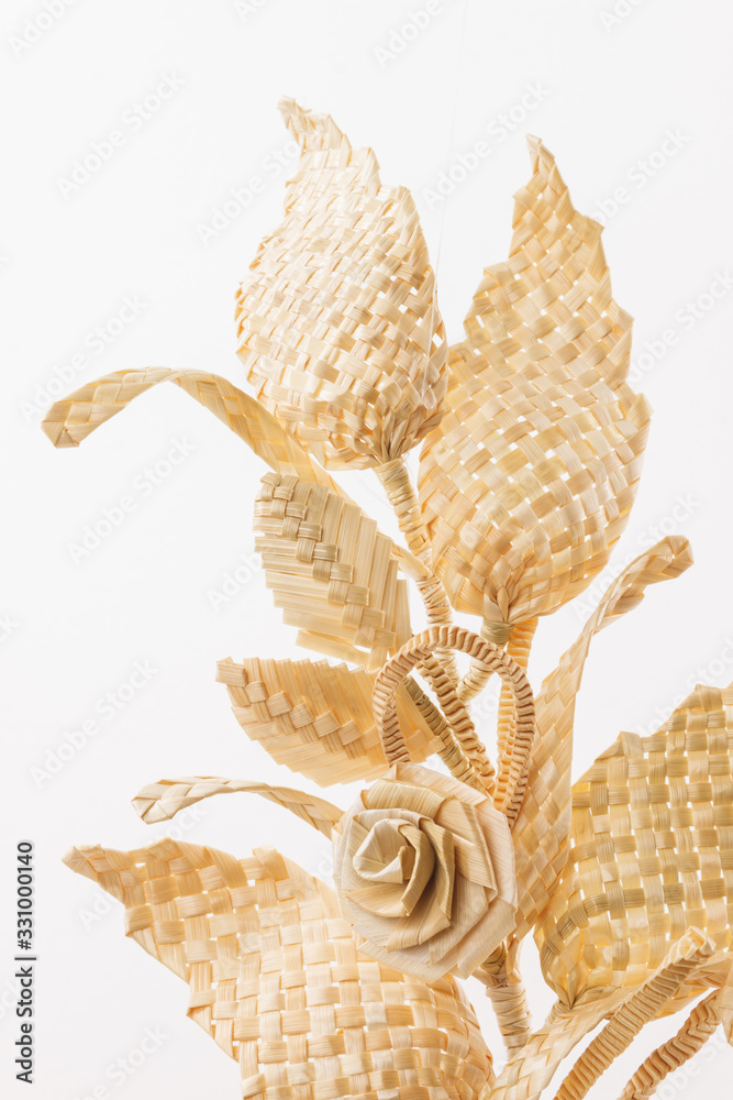 Obraz premium Decoration of straw on a white background. Branch with leaves and flowers is made of straw. Decor. Fragment closeup. Copy space 