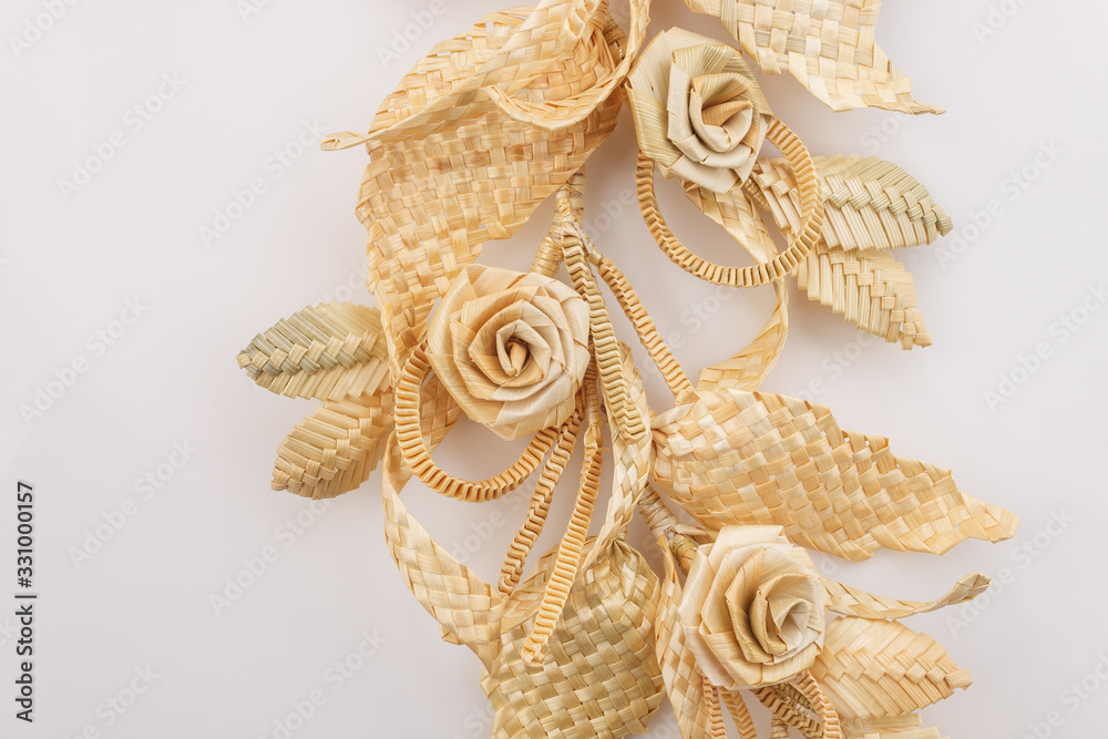 Decoration of straw on a white background. Branch with leaves and flowers is made of straw. Decor. Fragment closeup Decoration of straw on a white background. Branch with leaves and flowers is made of straw. Decor. Fragment closeup