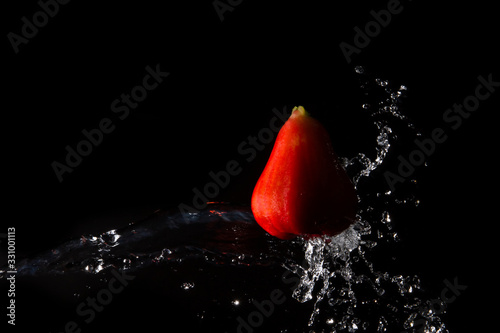 The water is splashed rose apple  on the  until the water is distributed beautifully on a black background.