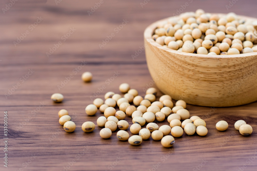 Soy beans in wooden bowl isolated on wood table background. Soy beans in wooden bowl isolated on wood table background.