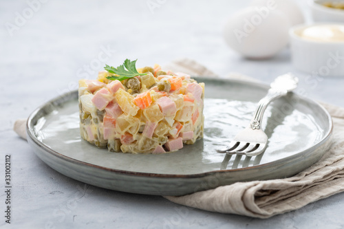 Russian salad Olivier with mayonnaise served in culinary ring on plate. Light background.