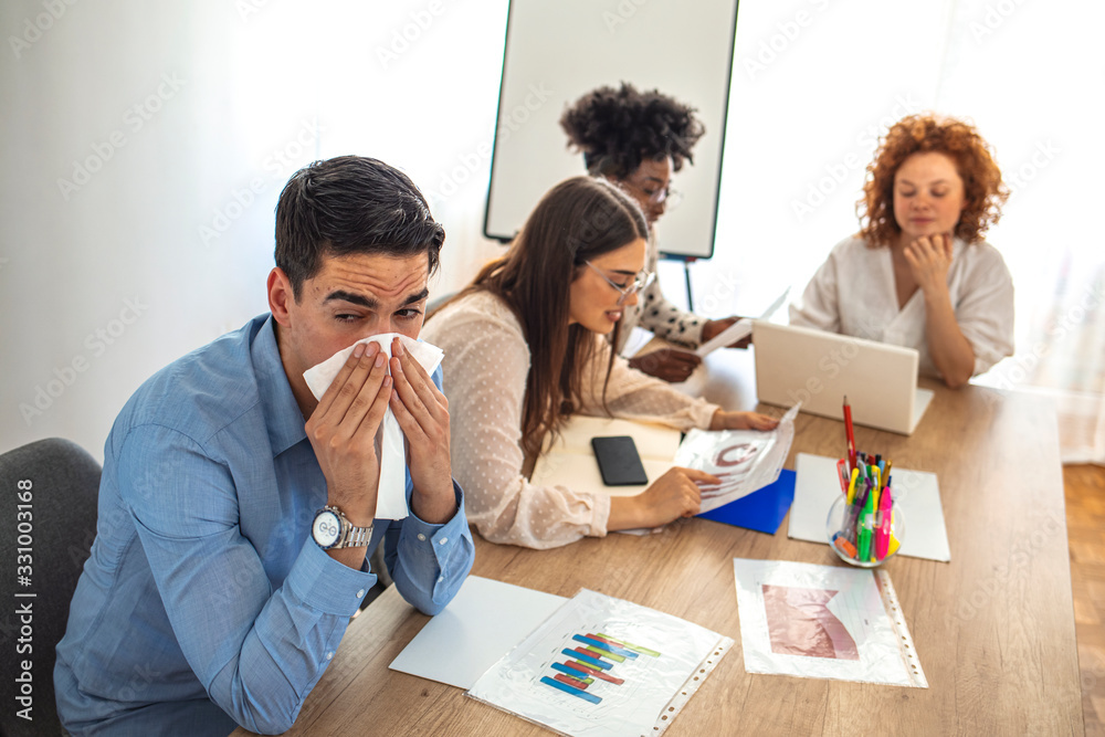 Cropped shot of a businessman suffering with allergies in an office. Shot of a frustrated businessman using a tissue to sneeze in while being seated in the office. Working when sick Cropped shot of a businessman suffering with allergies in an office. Shot of a frustrated businessman using a tissue to sneeze in while being seated in the office. Working when sick