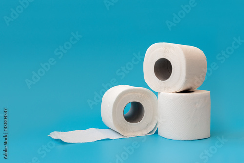 Several rolls of toilet paper lying on blue background. Copy space