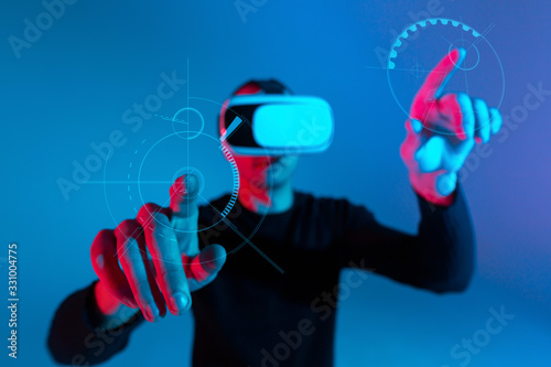 VR, AR, MR, XR-  Future technology. Neon. European man's in VR-glasses in neon on gradient background. Male portrait. Concept of human emotions, facial expression, modern gadgets and technologies