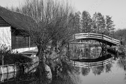  wooden bridge over the river giving access to the house in black and white