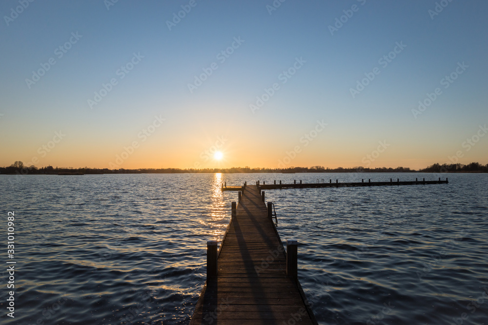 Pier at sunset over Lake Elfhoeven, part of lake area Reeuwijkse Plassen near Gouda, Netherlands