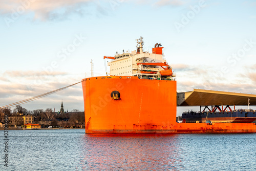 Photography Seascape closeup side view of a large orange semi-submersible heavy-lift ship with large load entering harbor in Stockholm Sweden
