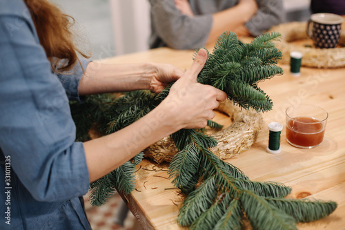 Base for Christmas wreath. Christmas decorations. Christmas wreath. Florist making Christmas wreath. View of female hands make a wreath.