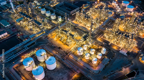 Aerial top view oil and gas tank with oil refinery background at night, Business petrochemical industrial, Refinery factory oil storage tank and pipeline, Ecosystem and healthy environment concepts.