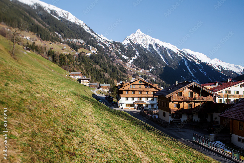 Wooden houses on a background of mountains. Austria. Warm winter.