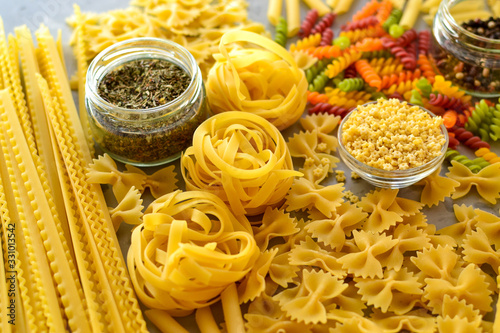 Italian raw pasta, types of pasta. Light background, top view, close-up. Farfalle, fettuccine, fusilli, colored pasta, tagliatelle.
