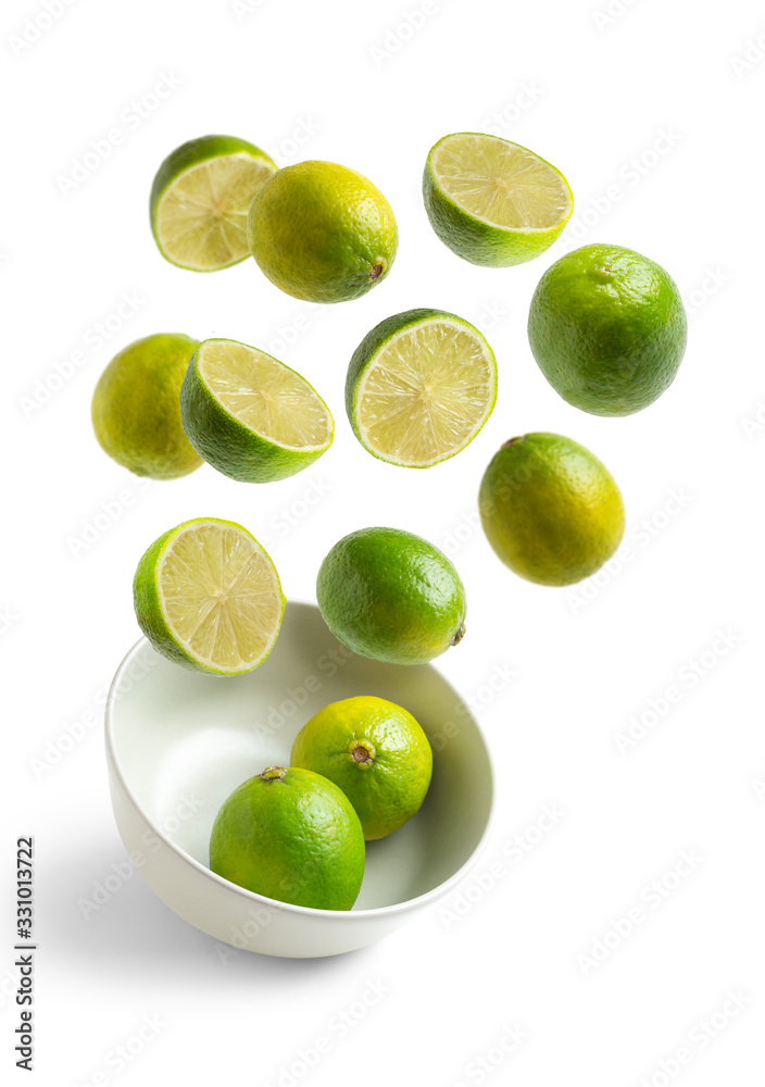 limes flying in white bowl on white isolated background