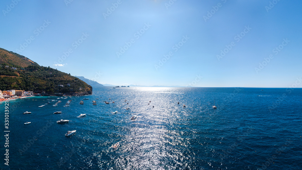 Aerial view of coastline of the village of Nerano. Private and wild beaches of Italy. Turquoise, blue surface of the water. Vacation and travel concept. Boats on raid in bay. Copy space. Summer day