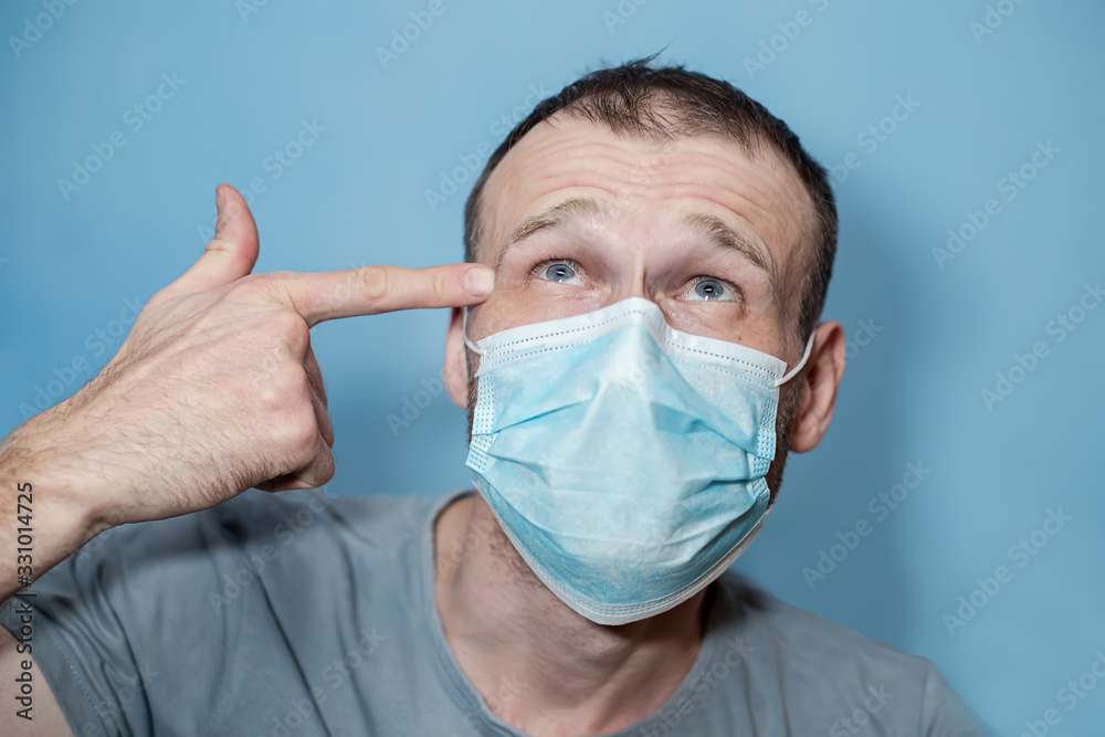 man in protective mask put finger to temple like suicide. guy in medical mask putting, holding pistol figure with fingers man in protective mask put finger to temple like suicide. guy in medical mask putting, holding pistol figure with fingers
