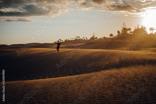Maspalomas, Canary Islands. Man stands in desert dunes at sunset with very orange tones