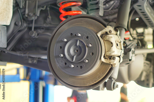 Disc brake of the vehicle for repair, in process of new tire replacement. Car brake repairing in garage.Selective focus disc brake on car, in process of new tire replacement.Close up.