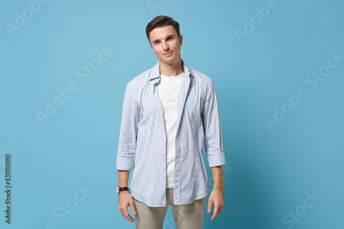 Attractive confident young man guy 20s in casual shirt posing isolated on pastel blue wall background studio portrait. People sincere emotions, lifestyle concept. Mock up copy space. Looking camera.