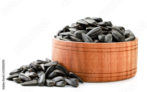 Sunflower seeds in a wooden plate and scattered on a white. Isolated