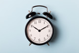 Black vintage alarm clock on blue background. Time concept