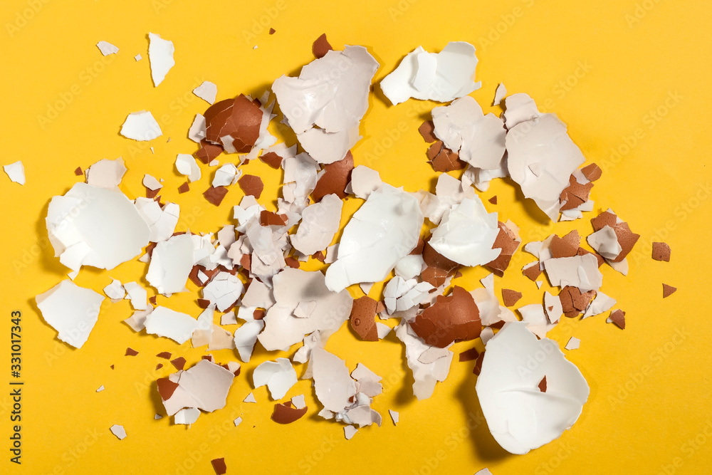 Egg shells of different sizes scattered on a bright yellow background. Top view Egg shells of different sizes scattered on a bright yellow background. Top view