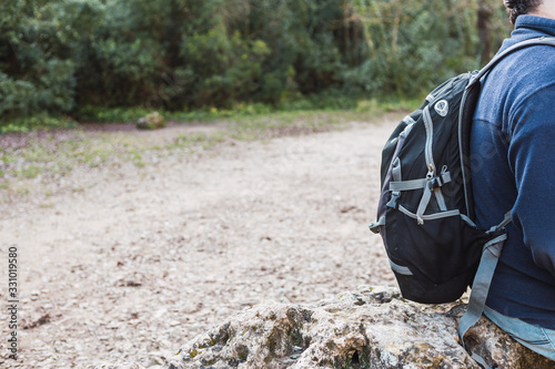 Portrait of an unrecognizable young man hiking in the forest with a backpack