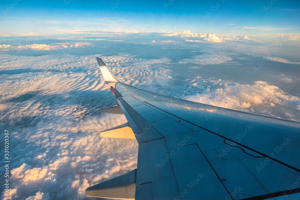 Silhouette wing of an airplane at sunrise view through the window.