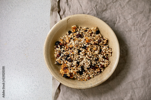 Fotografija Homemade crunchy puffed millet grain granola with dried fruits and nuts in ceramic bowl on grey linen cloth over white background