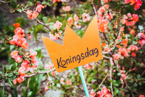 Paper cut crown with an inscription Koningsdag against the background of flowers © Alrandir
