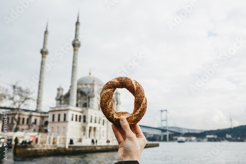Photography A man holds in his hand a traditional Turkish bagel called Simit against the bac