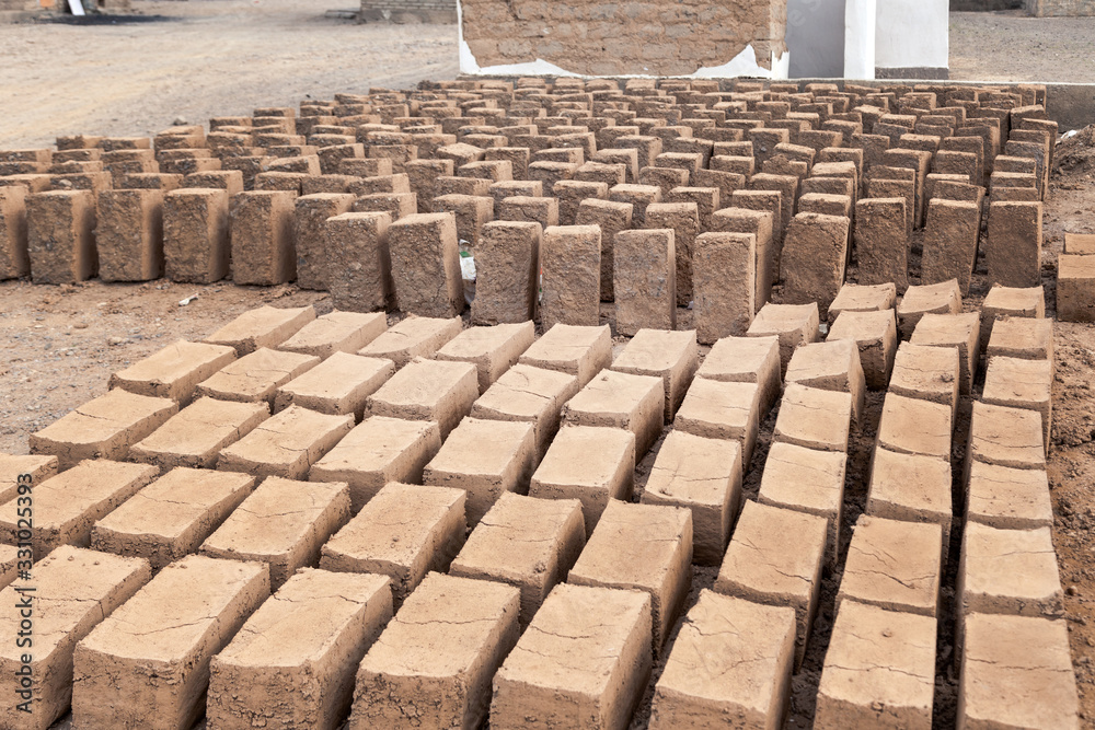 Traditional homemade production of raw clay brick laid out in stacks for drying on brick factory