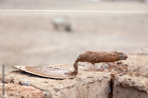 Trowel on wall of unfinished house from raw clay brick