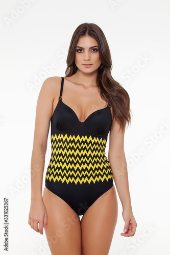 beautiful girl posing in stylish yellow detailed black swimsuit on white background.