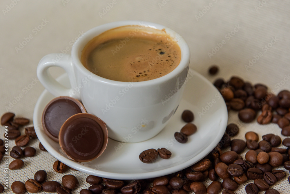 Latte coffee / cappuccino in a transparent glass with a pen on a wooden background. Coffee beans. Chocolate candies with nuts. Morning coffee concept. Latte coffee / cappuccino in a transparent glass with a pen on a wooden background. Coffee beans. Chocolate candies with nuts. Morning coffee concept.