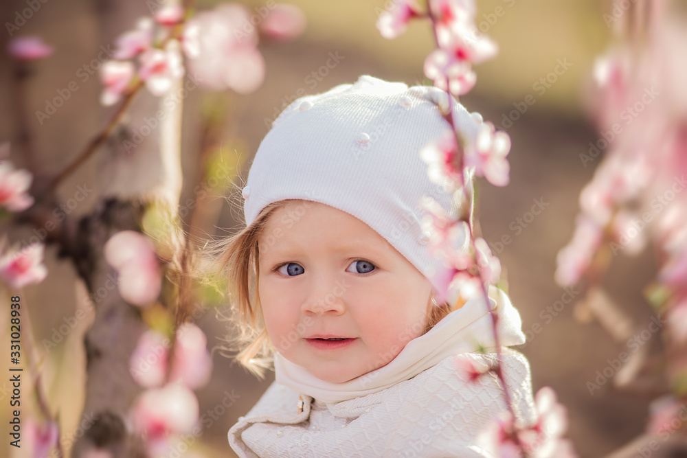Little girl on a walk among the flowering trees. The girl breathes fresh air. A healthy walk. Little girl on a walk among the flowering trees. The girl breathes fresh air. A healthy walk.