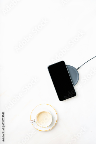 Smartphone on a charger and cup of coffee
