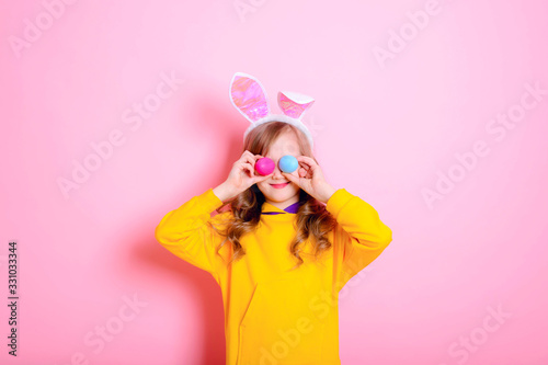 Funny girl kid blonde with Bunny ears holds bright Easter eggs. Happy Easter! Traditions, holidays, spring, religion concept. © NATALYA