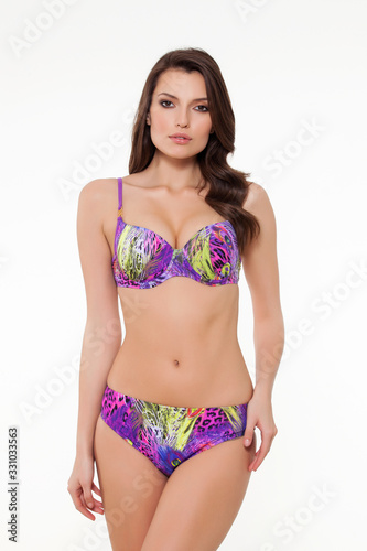 beautiful girl posing in stylish patterned chic purple bikini on white background.