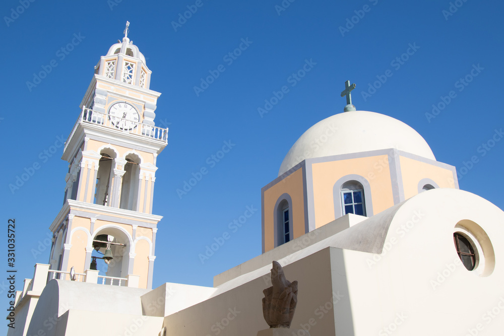 Dettaglio delle campane di una chiesa a Santorini, con bandiera greca e vista sul mare