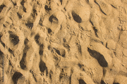Top view of yellowish brown textured sand with patterns at Jampore beach of Daman in India as background
