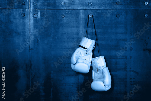 White leather boxing gloves hanging on blue wall