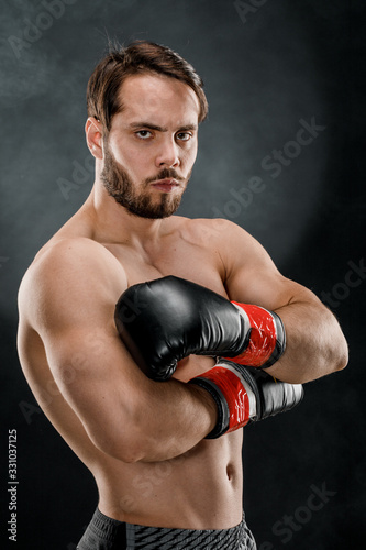 shirtless boxer with gloves on dark background in smoke